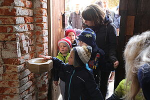 Kinder kommen in die Kirche und tauchen Finger ins Weihwasserbecken 